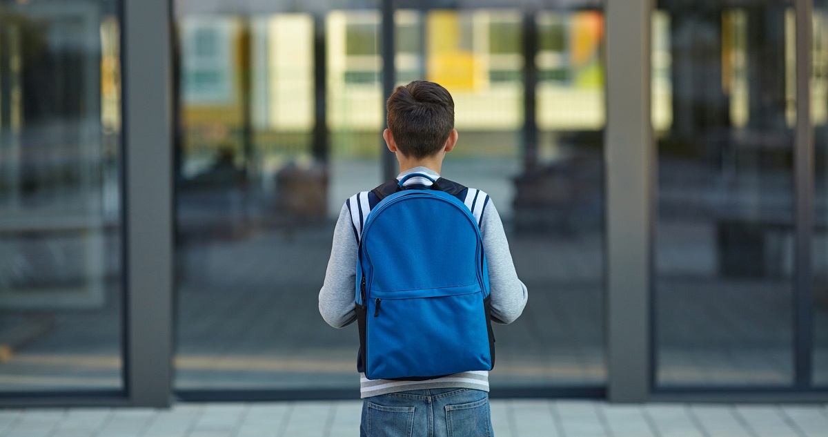 Kisfiú áll az iskola előtt