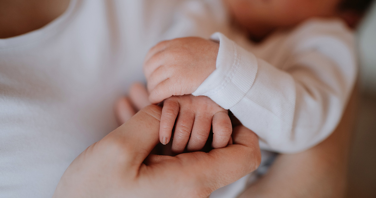 Anya karjában tartja a babát kezét fogja