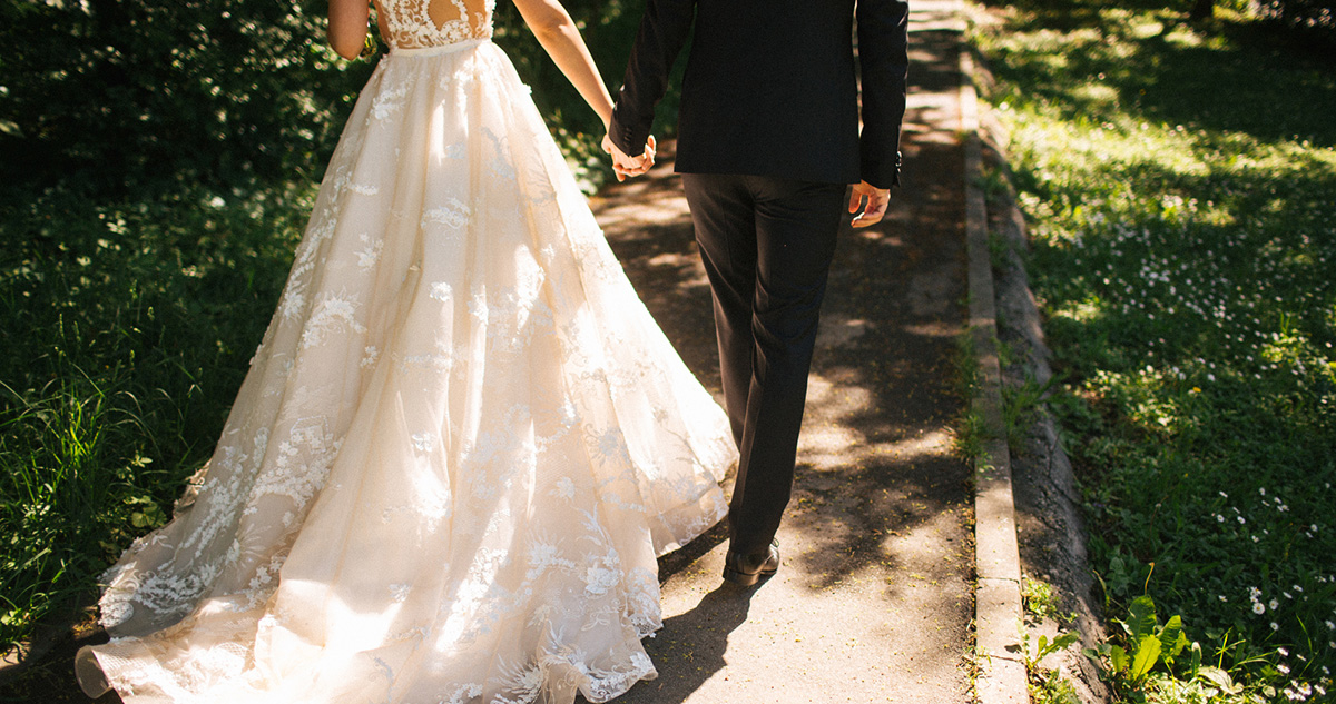 Esküvőn menyasszony, vőlegény kéz a kézben sétál