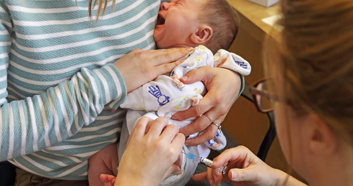 Kisbaba védőoltást kap, anyja a karjában tartja