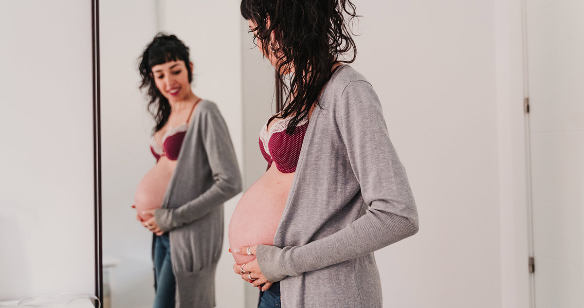 Terhes nő a tükörben nézi magát