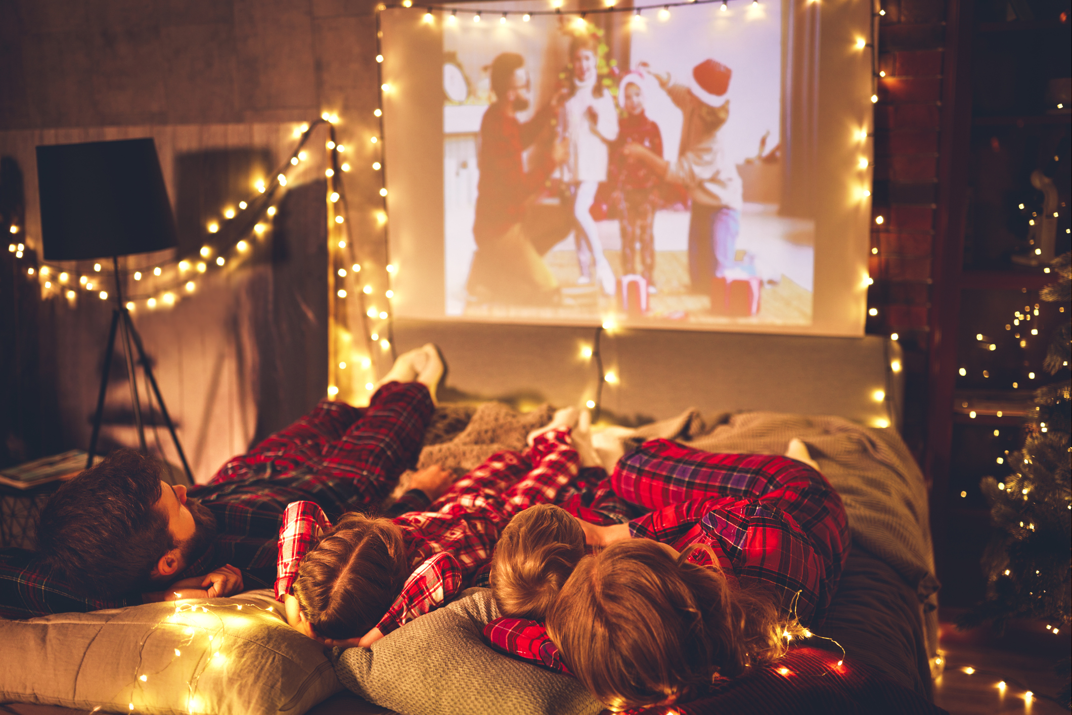 Család pizsamában együtt filmet néz otthon ünnep idején