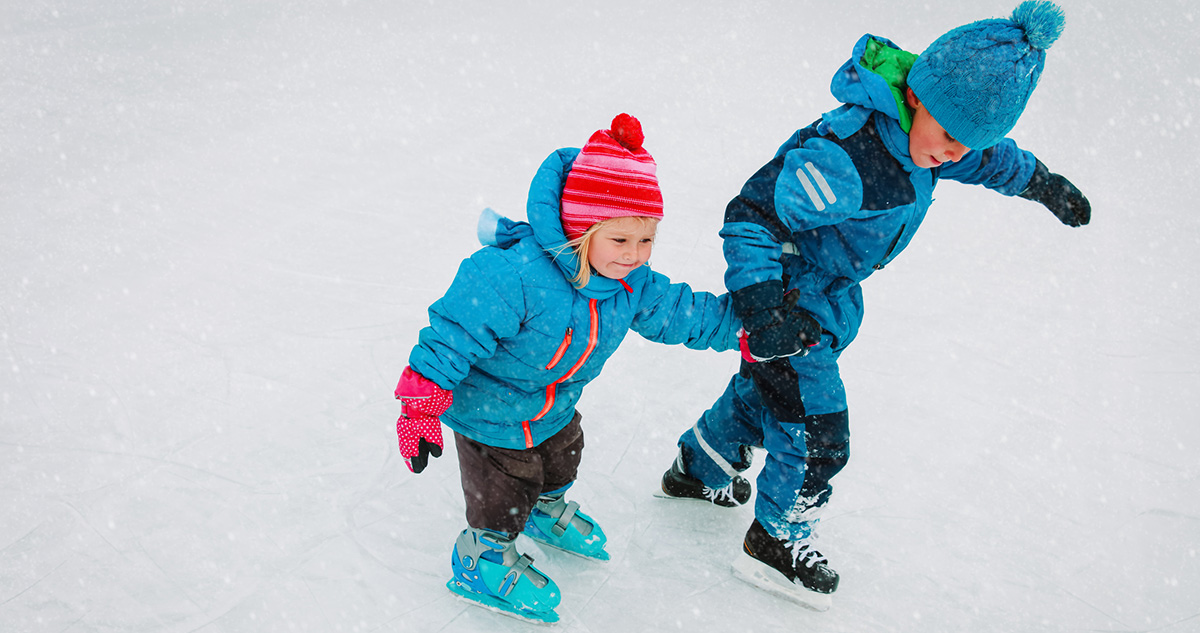 Gyerekek egymás kezét fogva korcsolyáznak