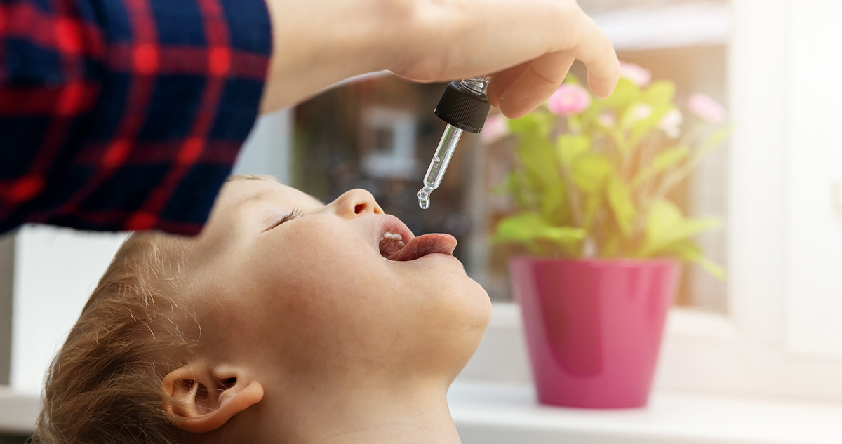 Kisgyereknek D vitamint cseppent a szájába az anya