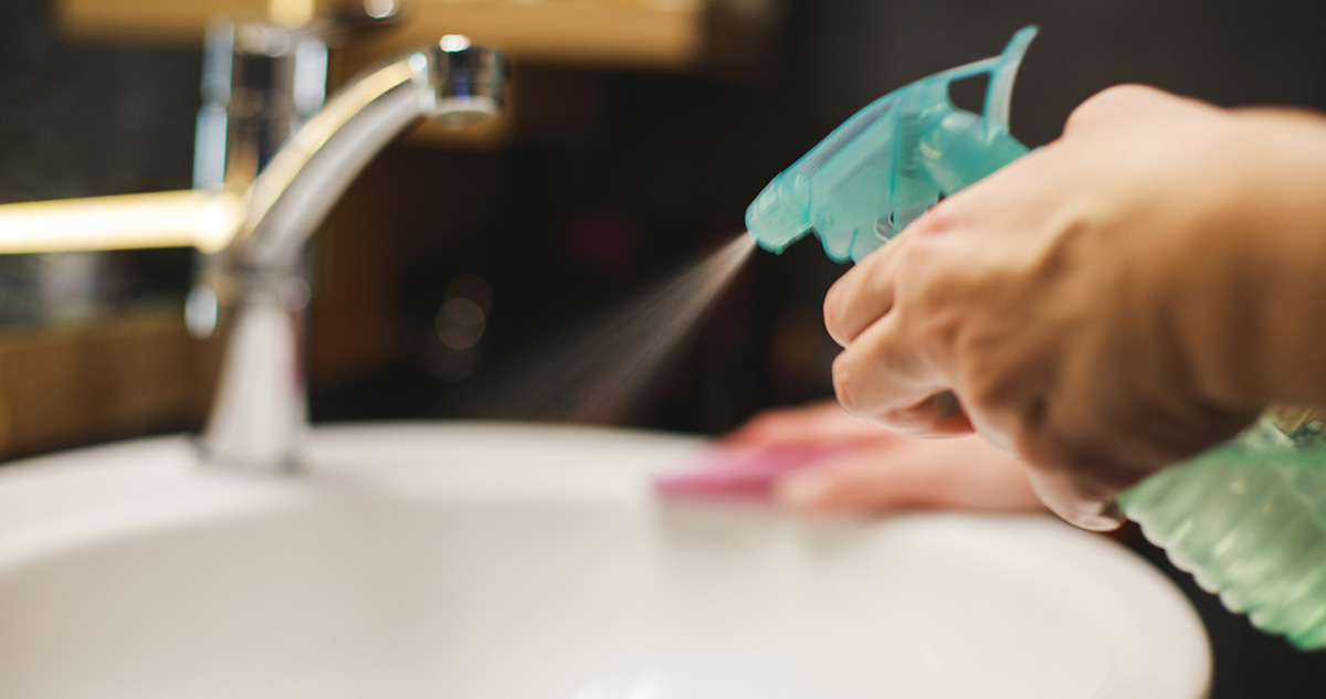 Nő szórófejes flakonnal takarítja a mosdót