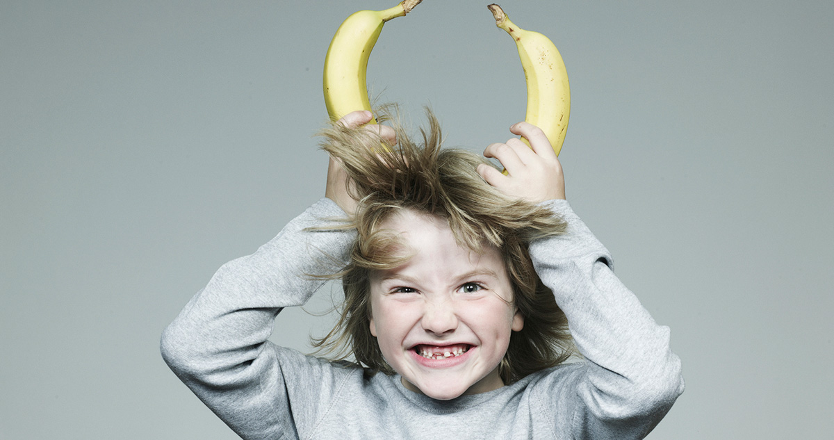 Fiú banánokat tart a fejéhez nevetve