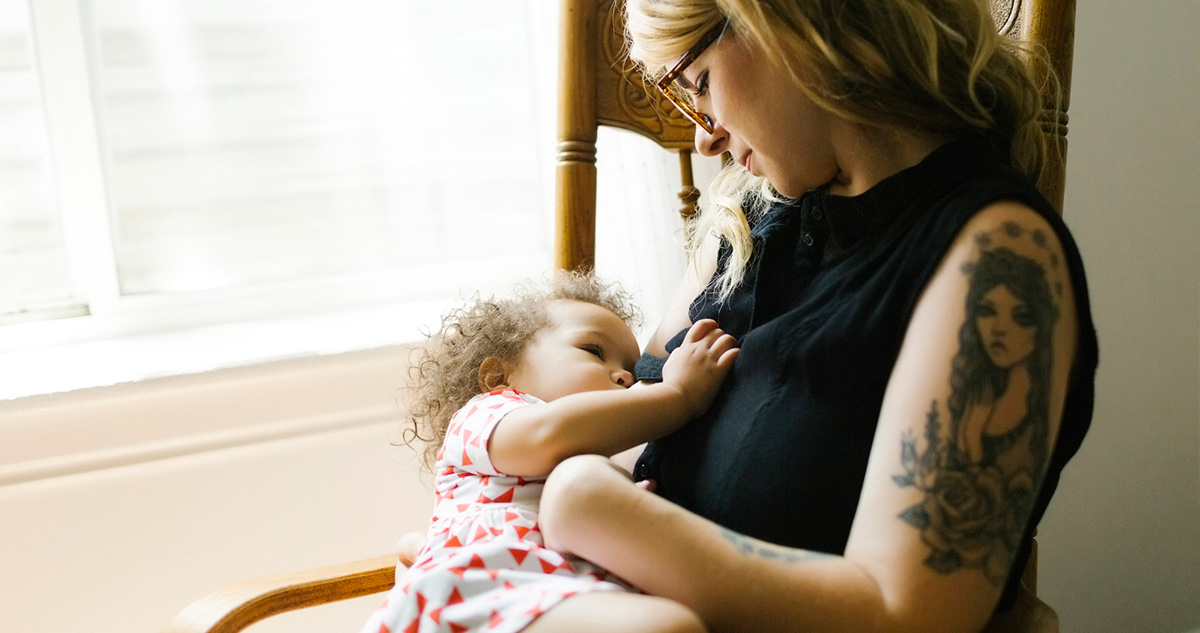 Tetovált karú anya szoptatja kislányát