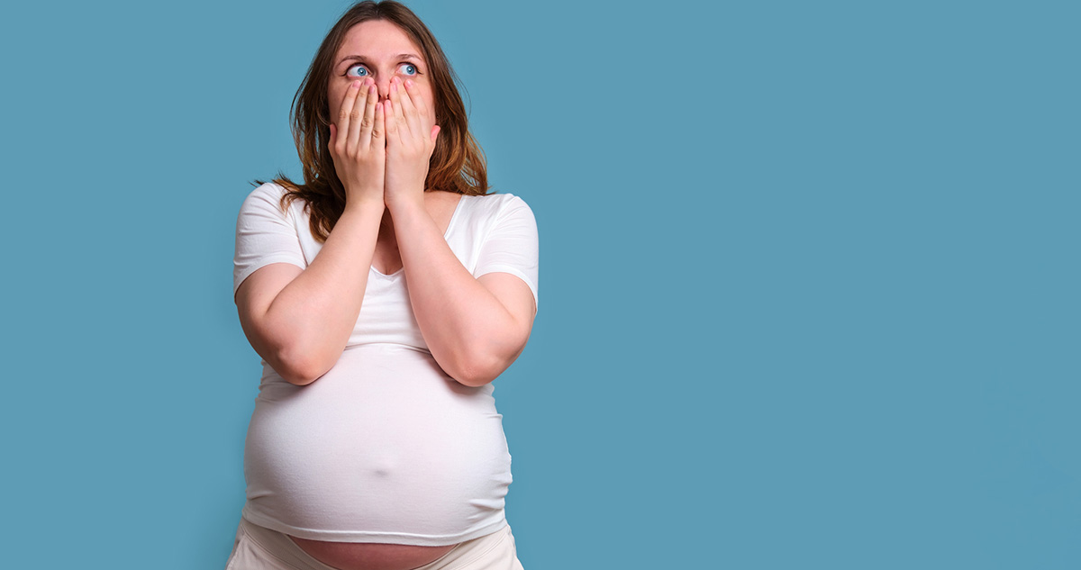 Terhes nő fehérben szája elő teszi kezeit meglepődik