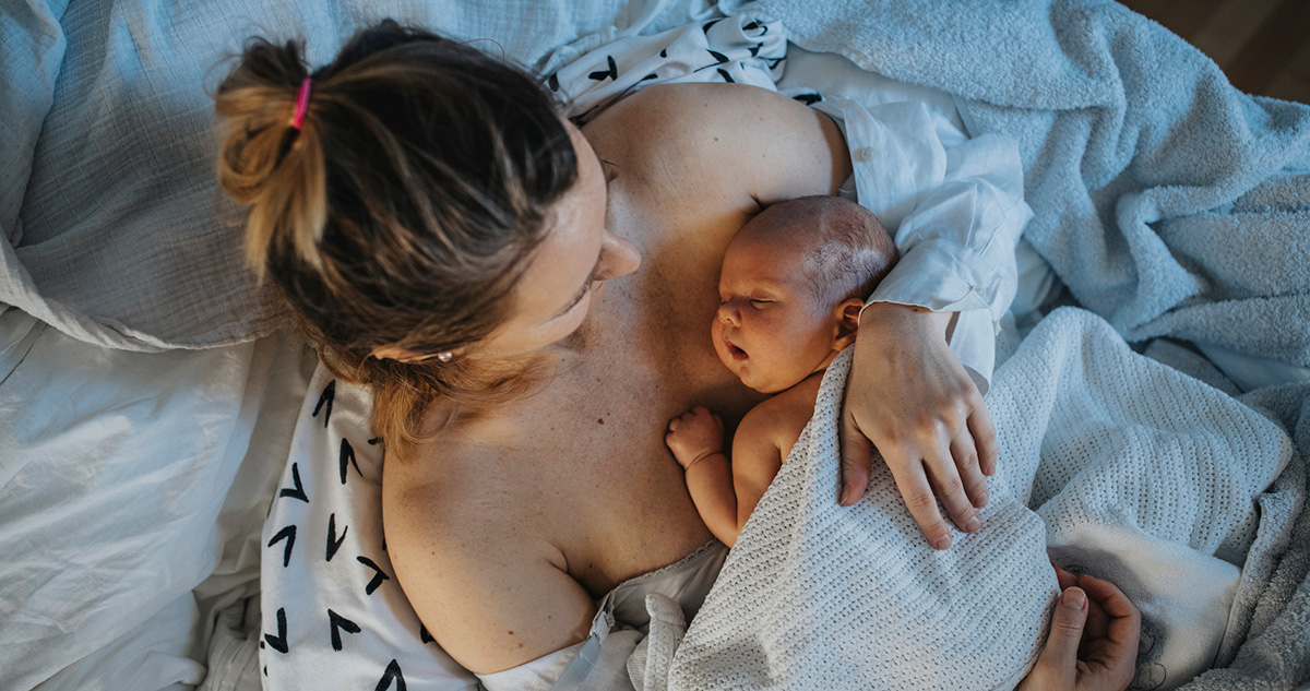 Újszülött baba anya karjában alszik