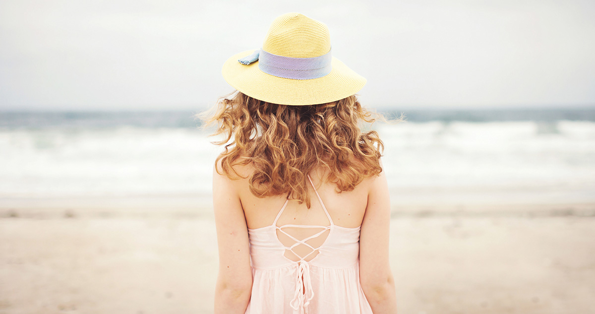 fiatal nő tengerparton, háttal, nyári ruhában