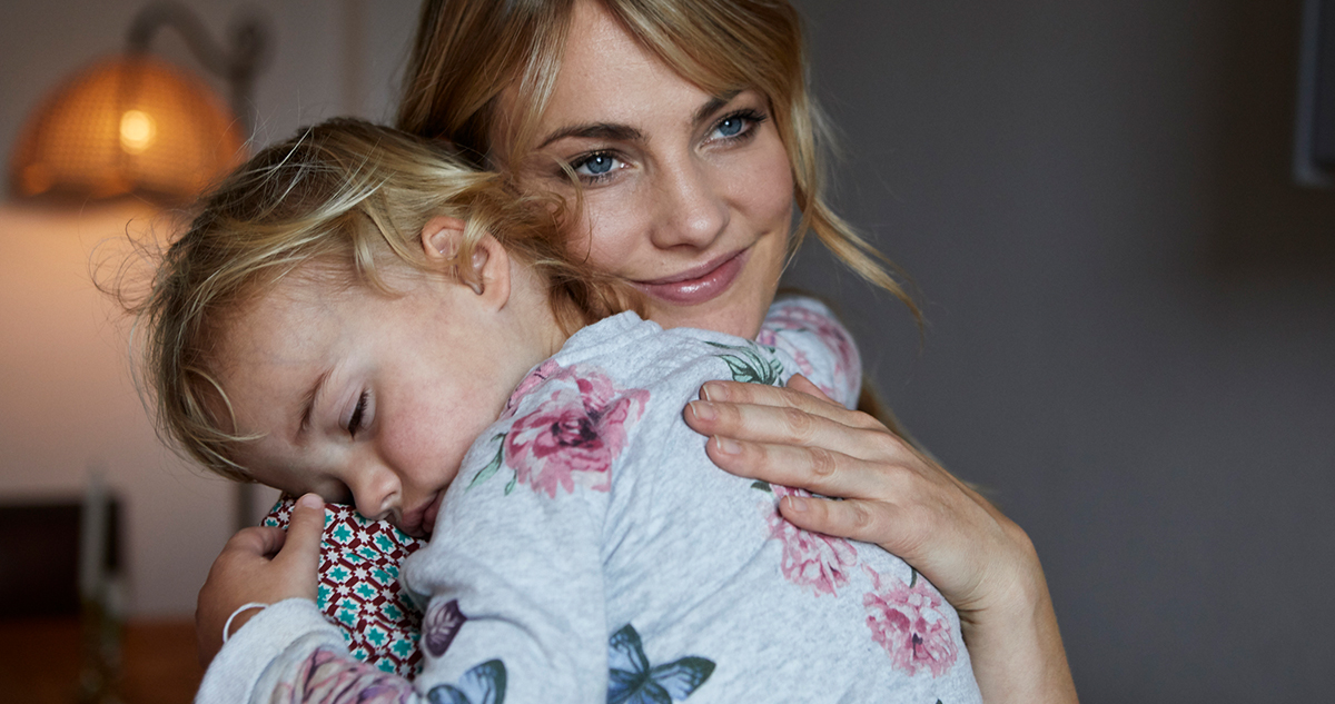 Fiatal nő alvó kislányt ölel