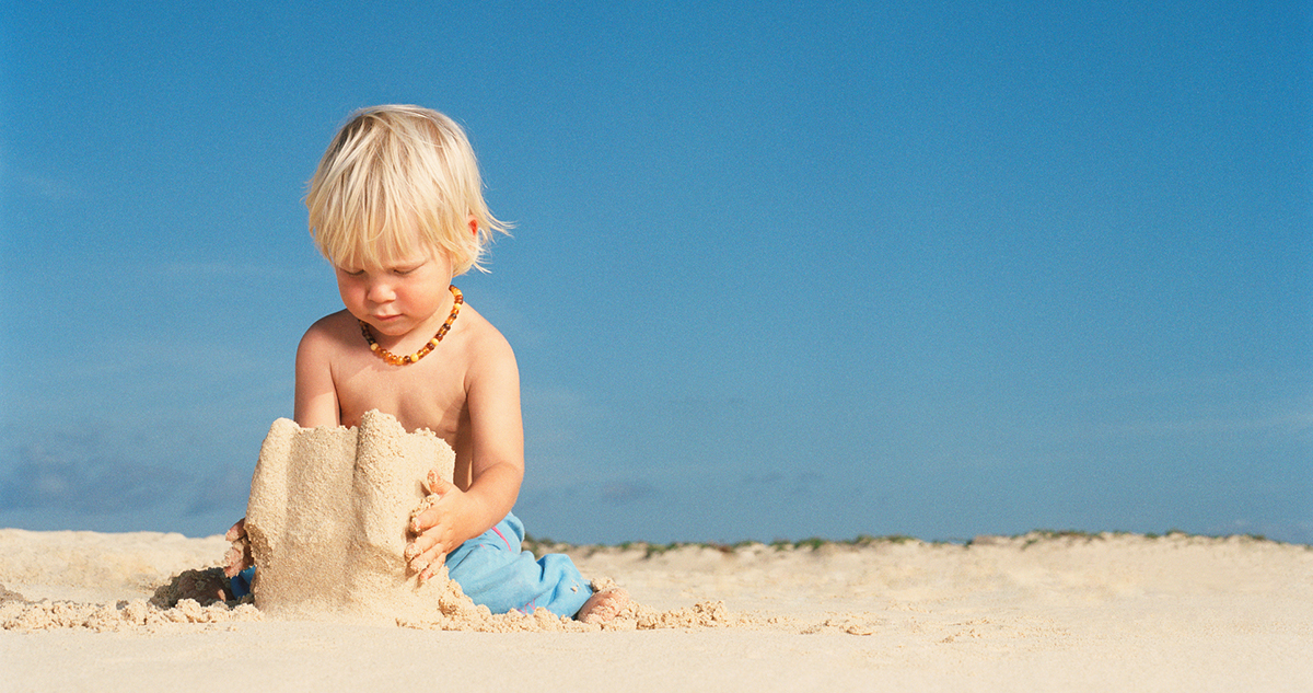 kisfiú homokvárat épít a tengerparton