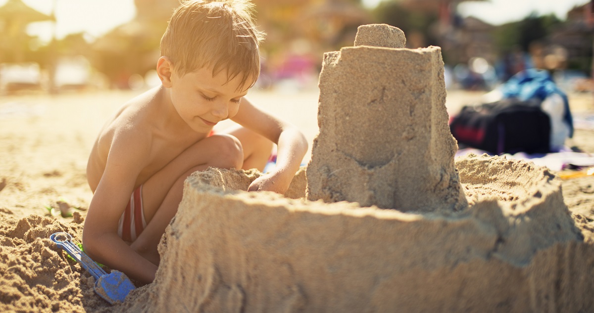 kisfiú várat épít a tengerparton