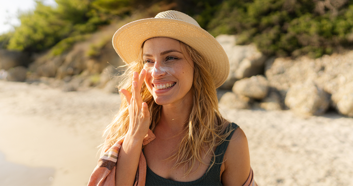 fiatal nő strandon fényvédőt ken az arcára
