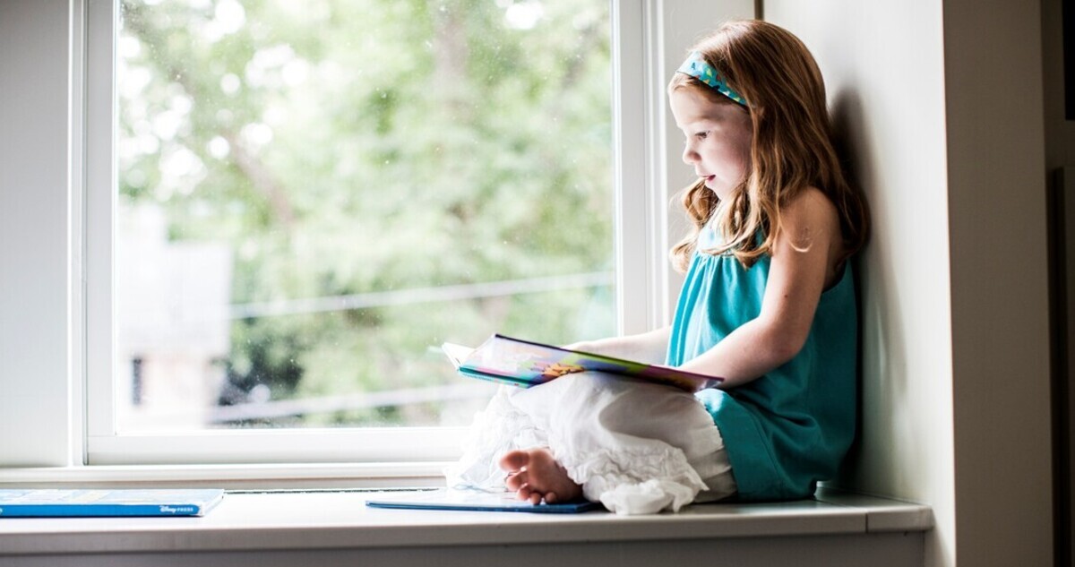 kislány olvas az ablakban