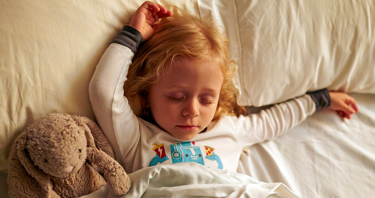 vörös hajú kislány alszik az ágyban plüss nyuszival