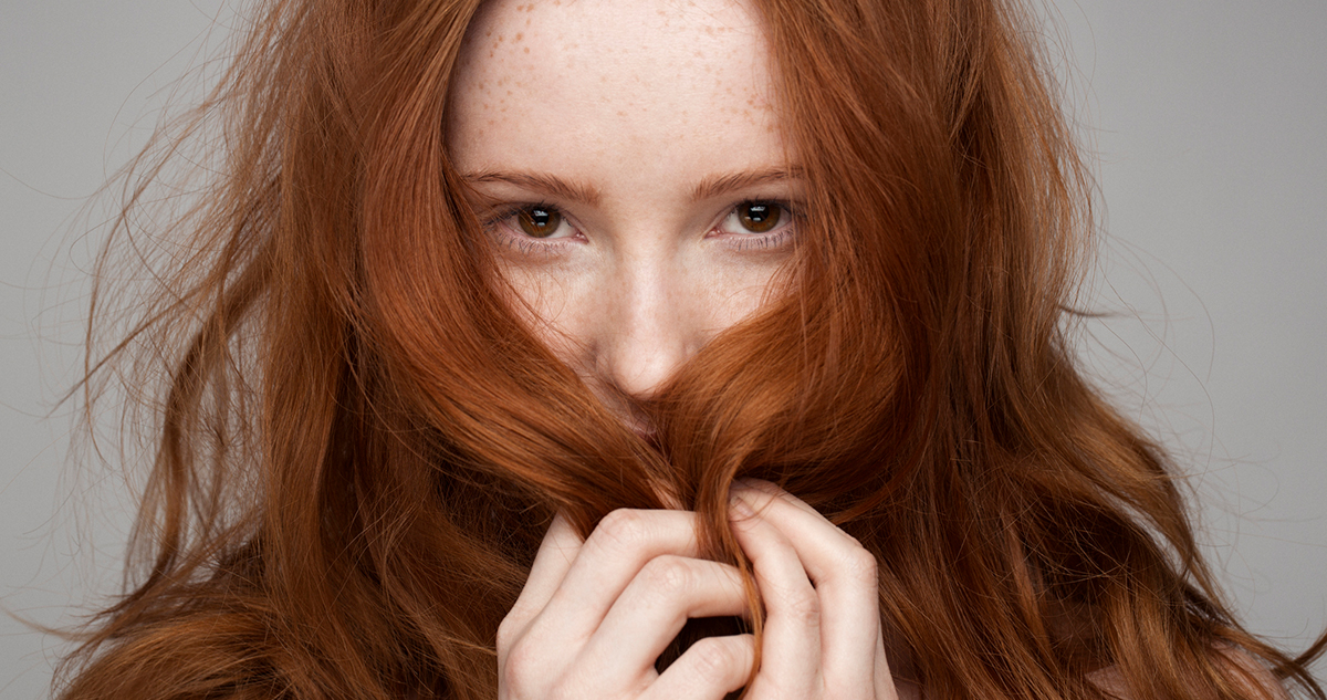 vörös hajú nő arcába húzott hajjal
