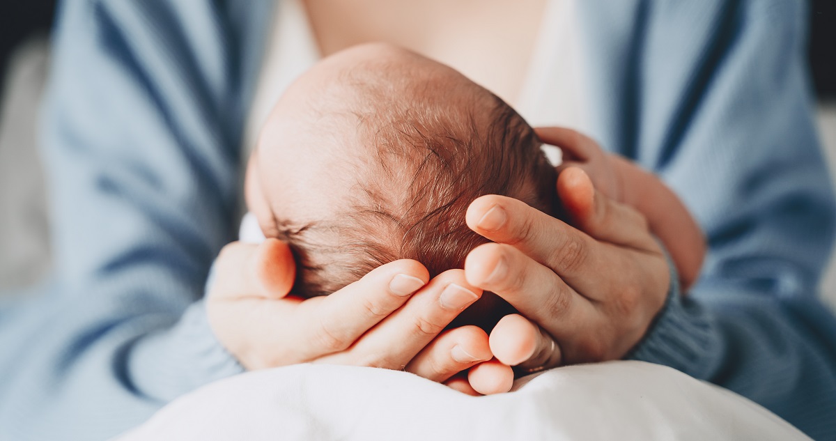 Újszülött babát tart a kezében egy anyuka