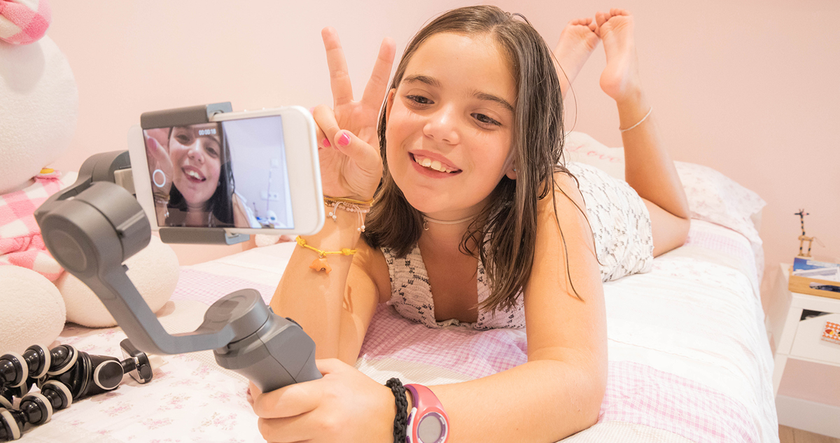 tini lány szelfit készít, videózik az ágyán fekve