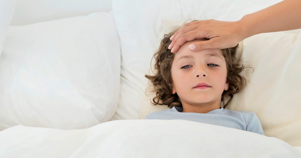 lázas, beteg kisfiú ágyban fekszik