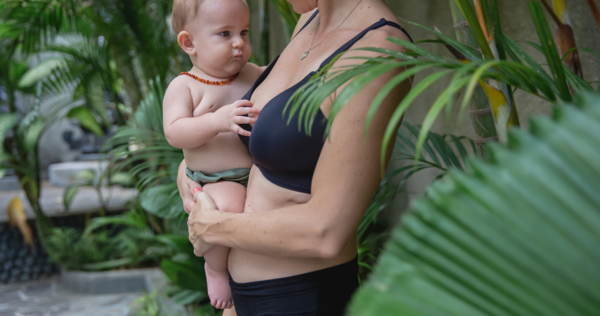 Fiatal nő fürdőruhában, kisbabával a karjában, szülés utáni test