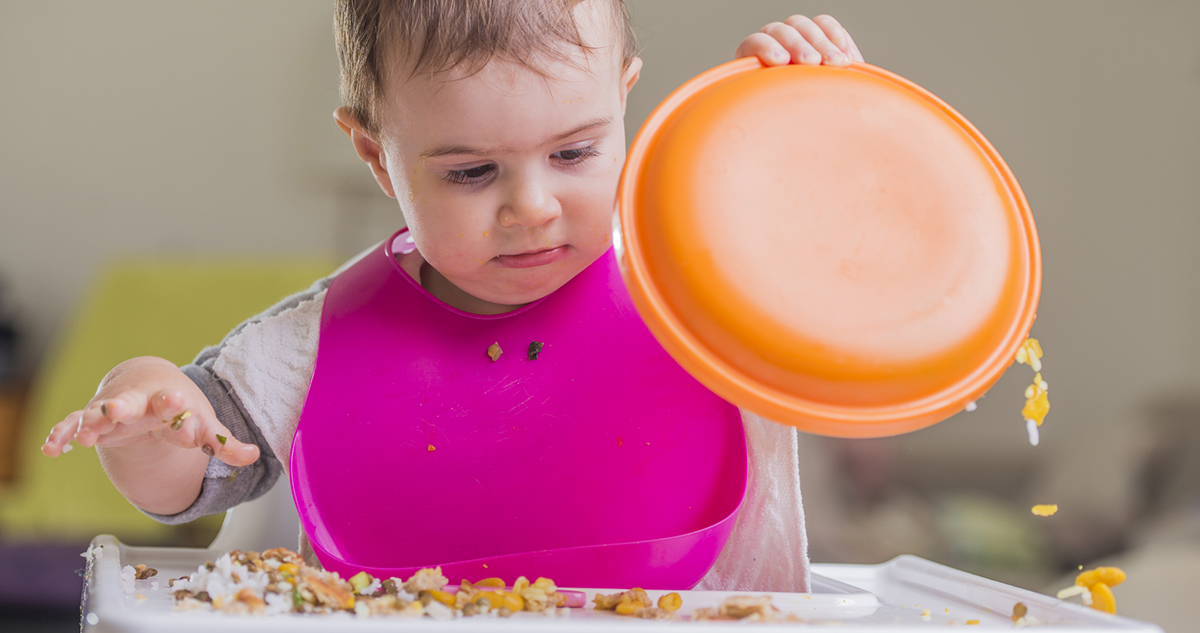 kislány evés közben kiborítja a tányérját, ledobálja az ételt