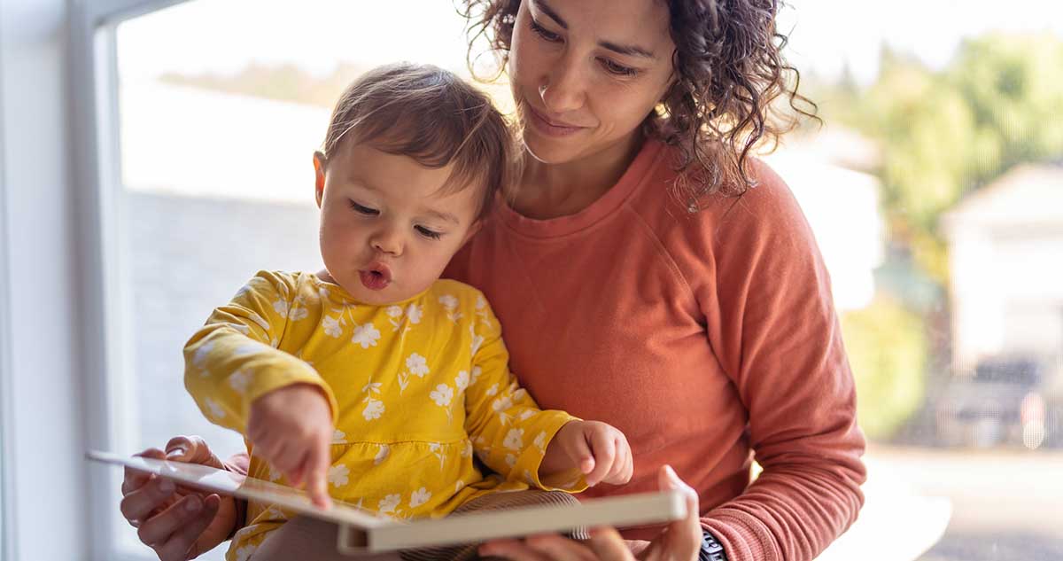 anyuka kislányával meséskönyvet olvas, érzelmi nevelés