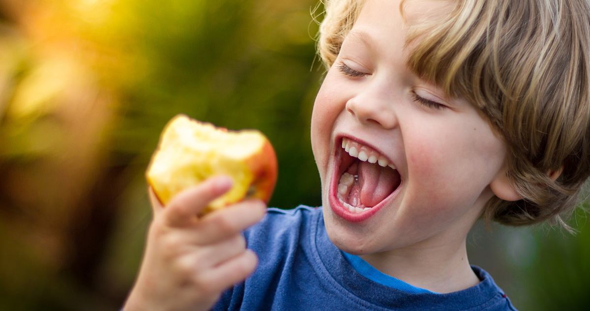 kisfiú almát eszik, nevet, egészséges szokások