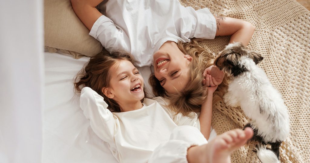 kislány anyukájával és kiskutyával, boldogan nevetnek