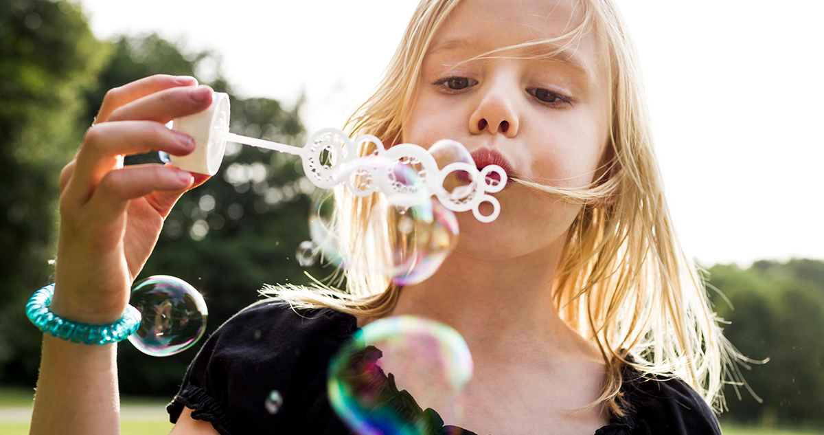 kislány buborékot fúj, nyári buborékfújós játékok