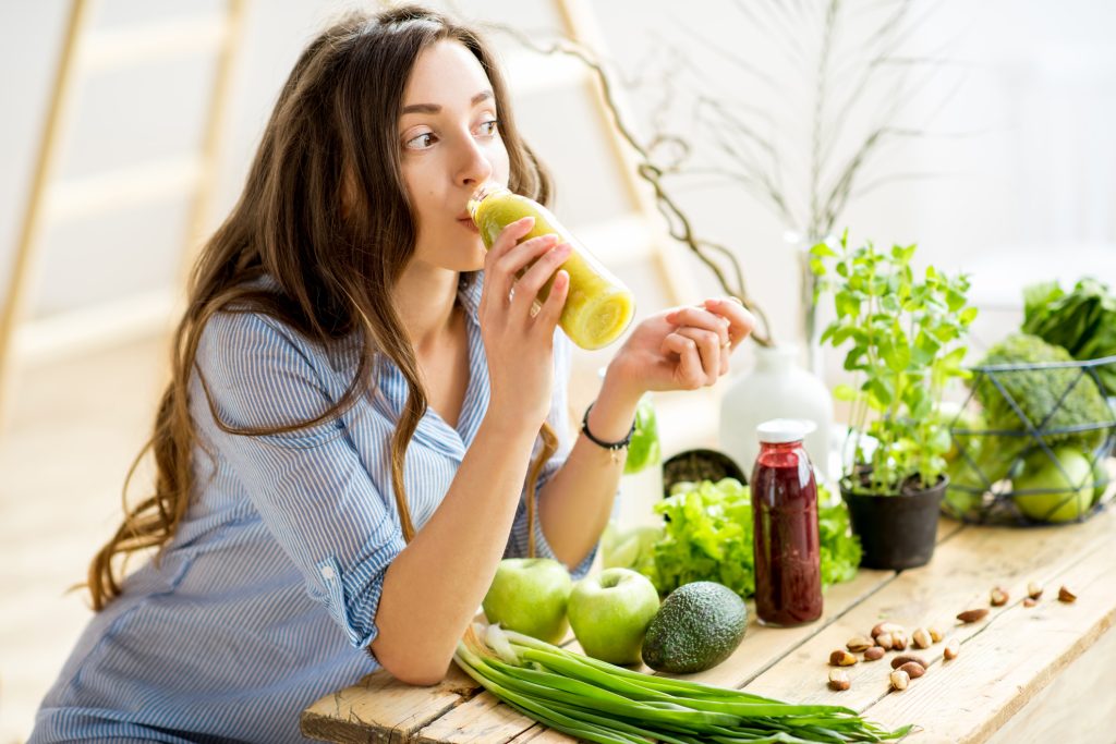 fiatal nő egészséges ételeket eszik, smoothiet iszik, teherbeesést segítő ételek