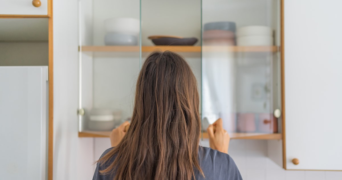 nő kinyitja a konyhaszekrényt