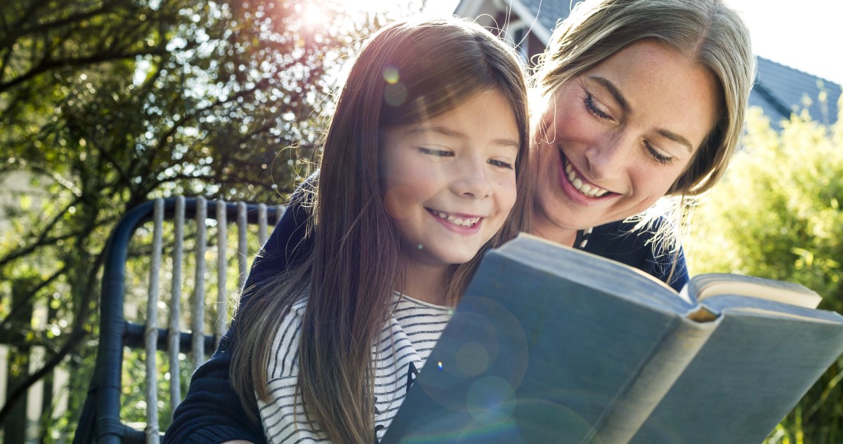 anya és kislánya olvasnak a kertben