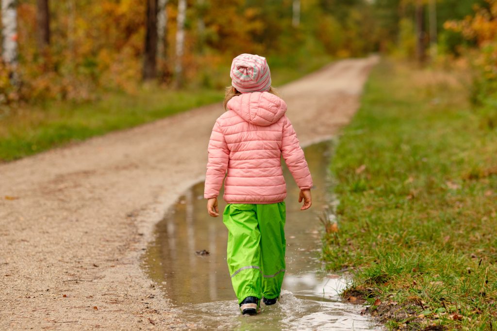 kislány esőben sétál vízálló ruházatban, esőnadrágok őszre