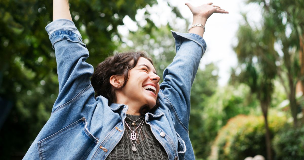 boldog nő karját a magasba tartja