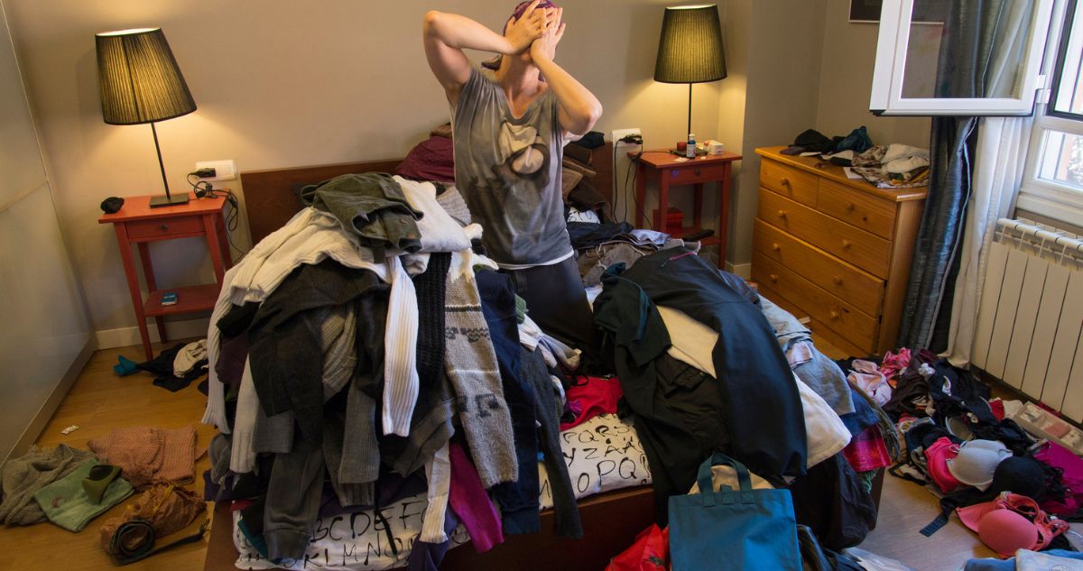 nő ruhakupac közepén ül a szobában