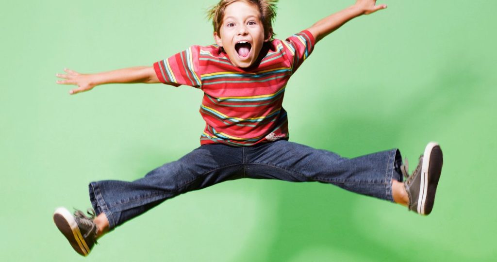 boldog kisfiú zöld háttérben felugrik