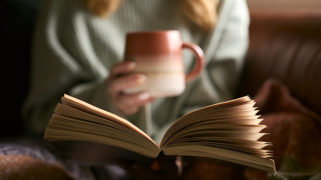 Nő könyvet olvas, nyitott könyv, bögre, meseolvasás