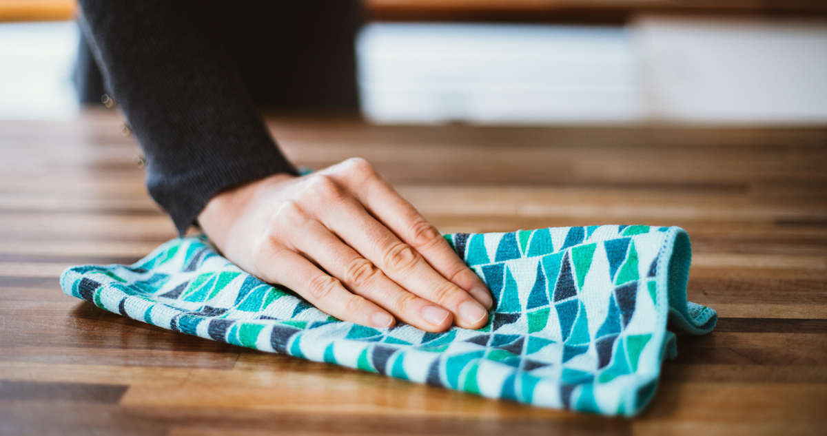 női kéz törli a port a bútorról