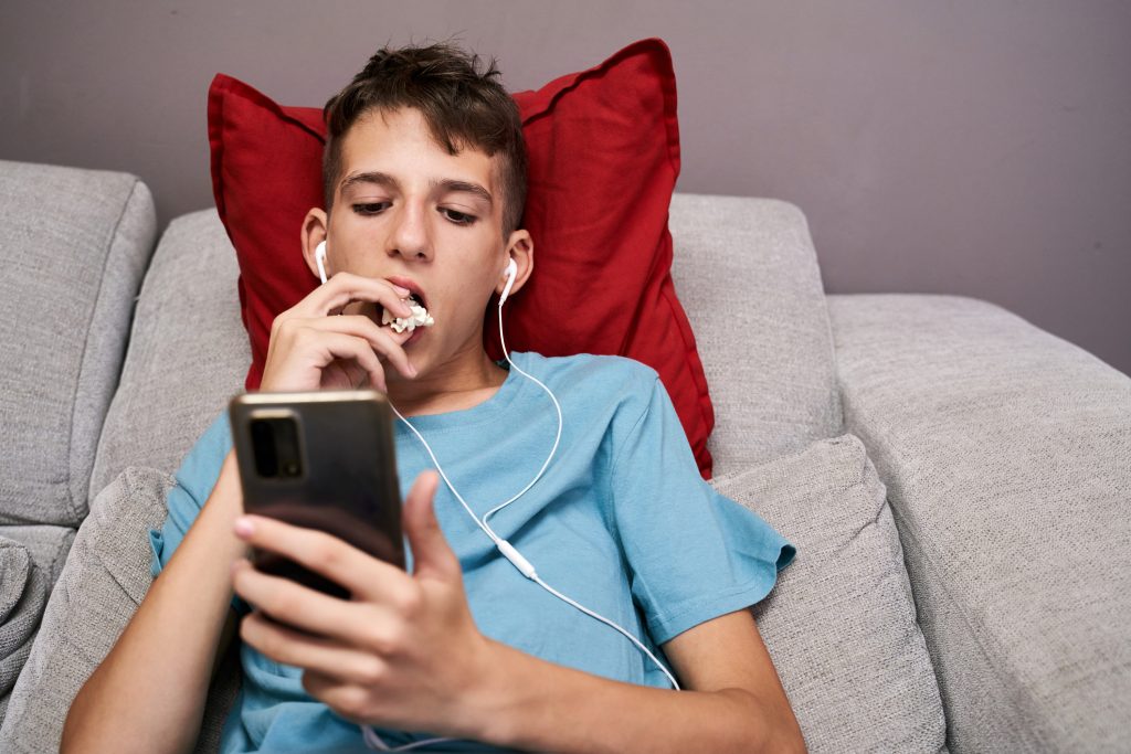 Az AI által generált tartalmak, különösen a rövid videók ma már a felnőtteket is könnyen megtévesztik - Gyerekszoba kamaszfiú telefonon filmet néz, AI videók felismerése