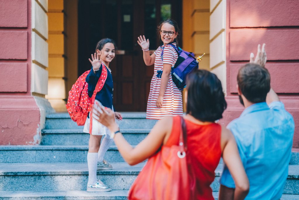 A búcsúmondat egyfajta útravaló, amely a szülőnek és a gyereknek is támogató segítség lehet a mindennapos "küldetések" teljesítéséhez. - Gyerekszoba kislányok integetnek az iskola előtt a szüleiknek, búcsúmondat