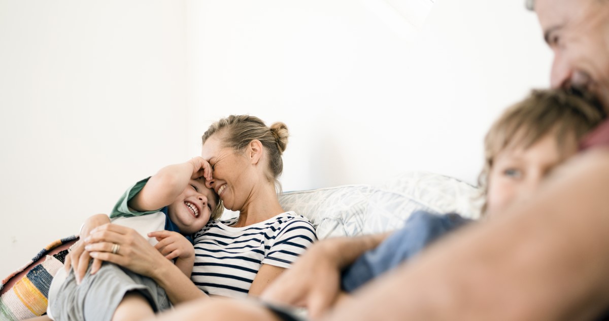 csalad - Gyerekszoba család a nappaliban, kanapén ülnek a szülők, két kisfiukkal