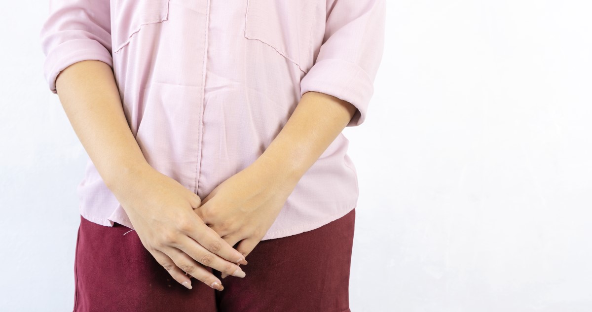 nő rózsaszín ingben és bordó nadrágban áll