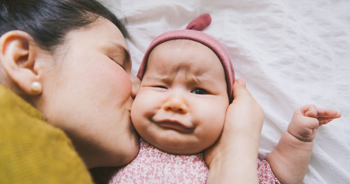 a baba vicces arcot vág, miközben az anyja puszilja