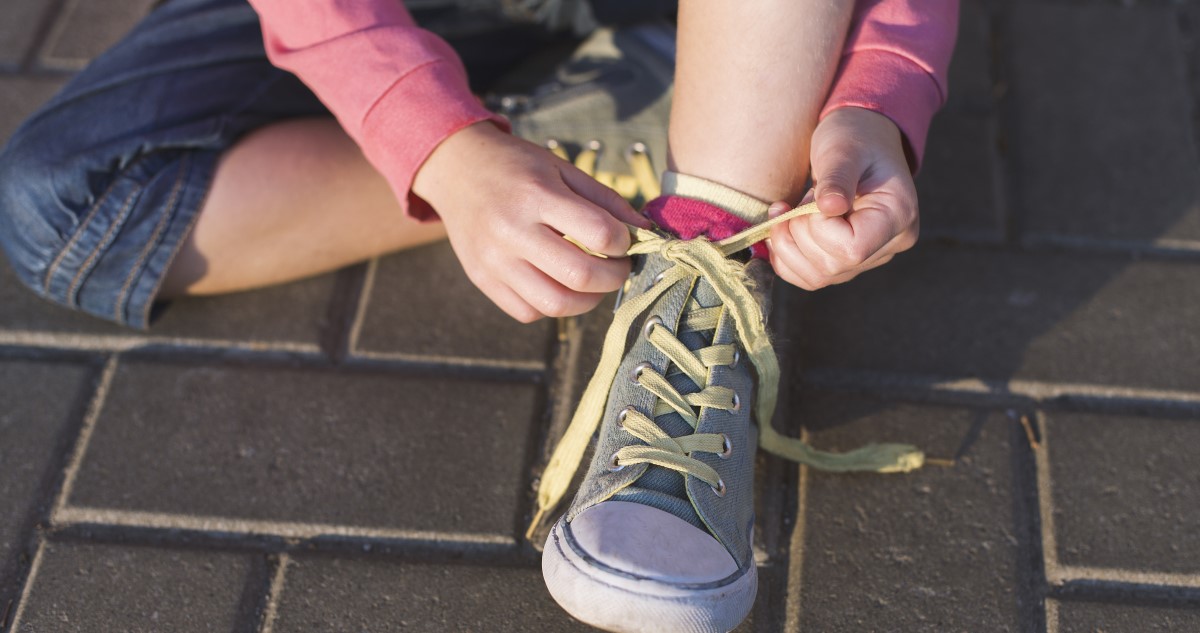 kislány beköti a tornacipője fűzőjét