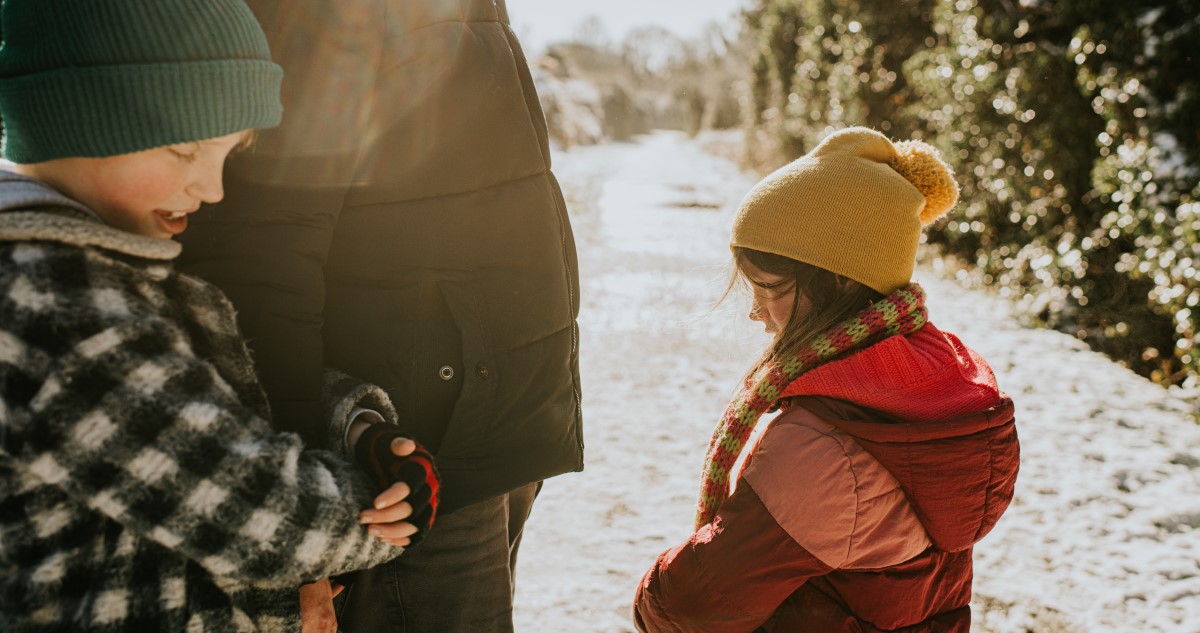 gyerekek kabátban sétálnak szülőjükkel szabadban télen