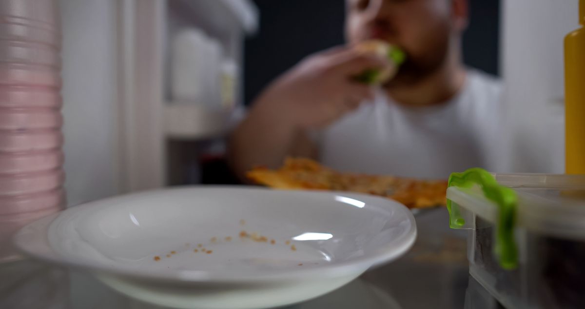 férfi éjjel eszik a nyitott hűtőből