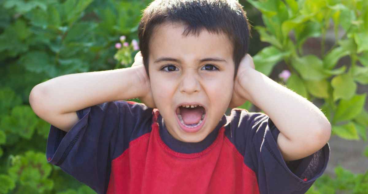 kisfiú kiabál miközben befogja a fülét
