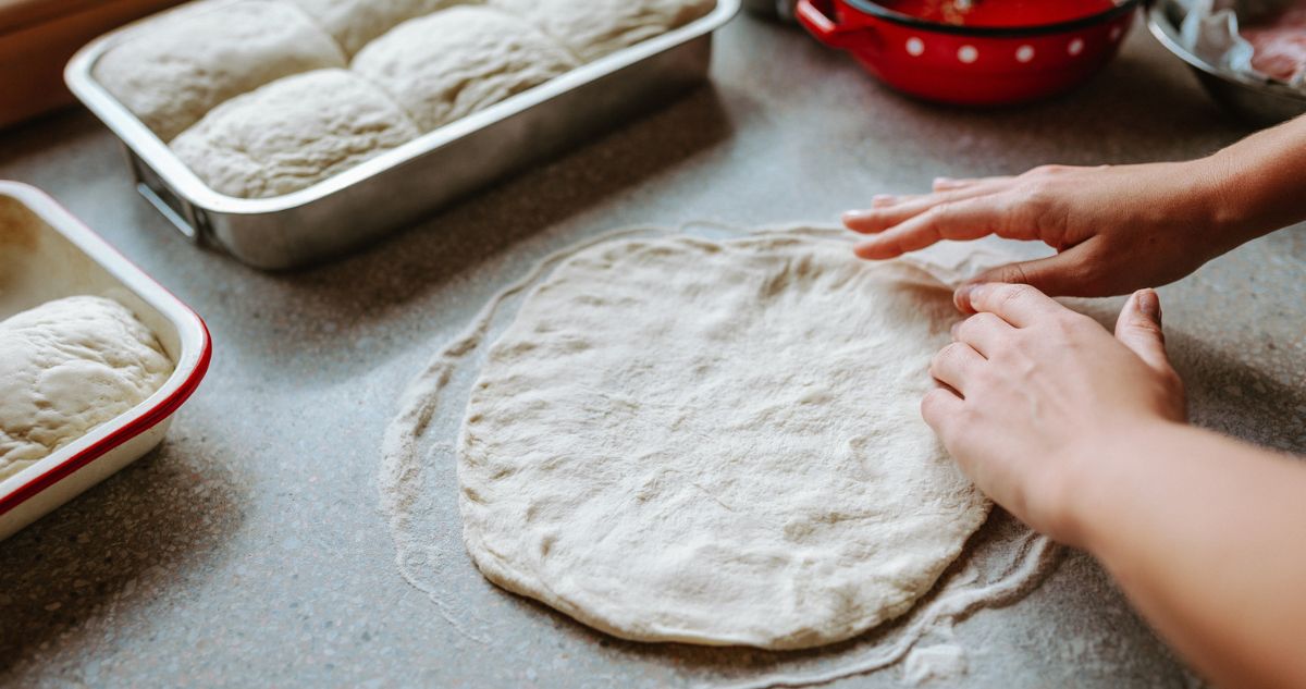 pizza tésztát nyújt a konyhapulton