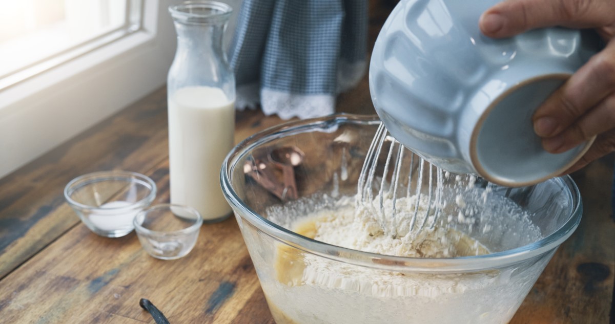 süteménytésztához lisztet kevernek egy kék tálból a konyhapulton
